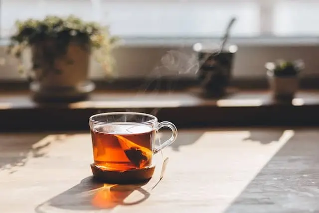 햇살에 비치는 위치에 김이 피어오르는 투명한 유리 잔 속에 갈색빛깔의 차 한잔